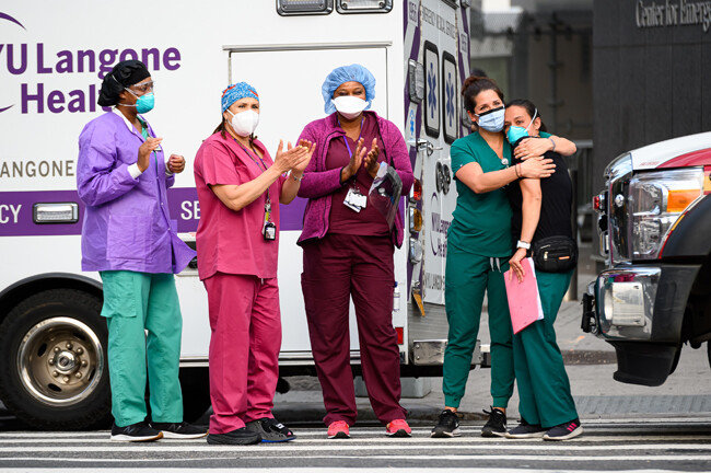 뉴욕에서 코로나바이러스 유행 당시 의료진과 필수 노동자들에게 감사를 표하기 위해 박수갈채를 보내는 동안 의료 종사자들이 뉴욕 주립 랑곤 병원 밖에 서 있다. [Getty Images]