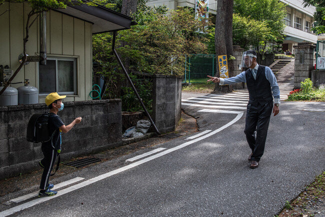 일본 닛코, 기누가와 초등학교 교장 다케다 사이오(오른쪽)가 2020년 6월 3일 일본 닛코에서 학교에 도착한 제자와 함께 가위바위보를 할 때 플라스틱 페이스 바이저를 착용하고 있다.