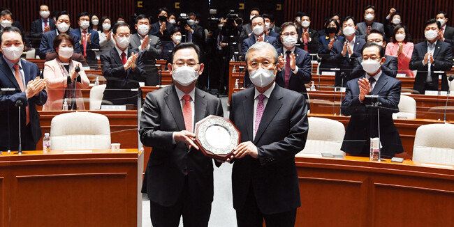 국민의힘 김종인 전 비상대책위원장(오른쪽)이 4월 8일 서울 여의도 국회에서 열린 의원총회에 참석해 기념패를 들고
사진 촬영을 하고 있다. [뉴시스]