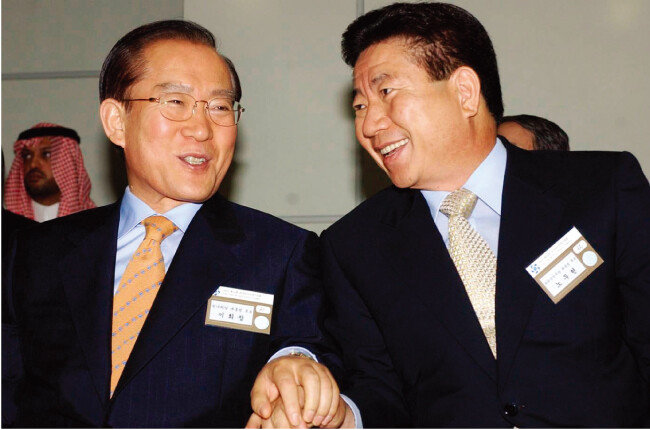 2002년 9월 29일 부산아시아드주경기장에서 열린 아시안게임 개막식에 참석한 당시 한나라당 이회창 대선후보(왼쪽)와 새천년민주당 노무현 대선후보가 손을 잡은 채 이야기를 나누고 있다. [동아DB]