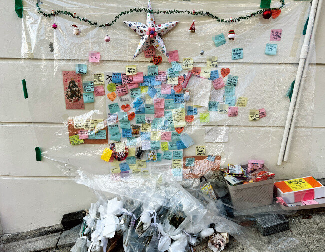 2022년 12월 27일 언북초 후문 근처 담벼락에 음주운전 차량에 치여 숨진 A 군을 추모하는 꽃과 메모, 간식이 놓여 있다. [이슬아 기자]