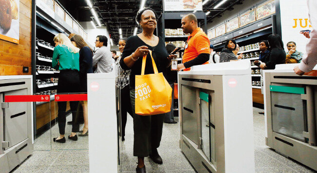 미국 뉴욕 ‘아마존 고’ 매장에서 한 고객이 장바구니를 든 채 앰비언트 컴퓨팅 기술이 접목된 자동결제 게이트를 지나고 있다. [뉴시스]