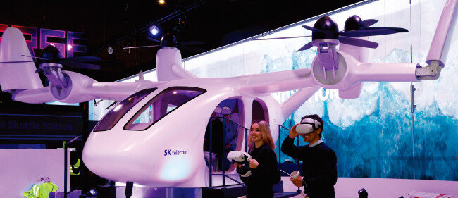 현지 관계자들이 SK텔레콤 전시관에서 조비 에비에이션의 기체를 기반으로 제작한 실물 크기의 도심항공교통(UAM) 모형을 체험하고 있다. [바르셀로나=사진공동취재단 최혁중 기자(동아DB 제공)]