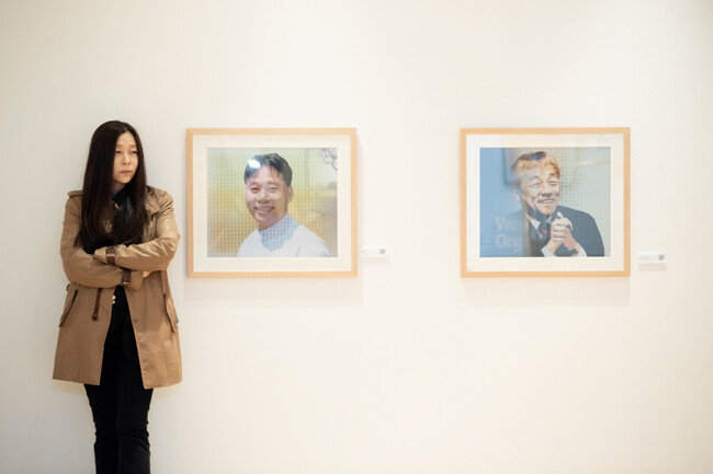 정유림 ‘바로 우리展’ 총감독이 콴리 작가의 렌티큘러 작품 ‘행복(이태석)’과 ‘In Action(이종욱)’ 옆에 서 있다. [지호영 기자]