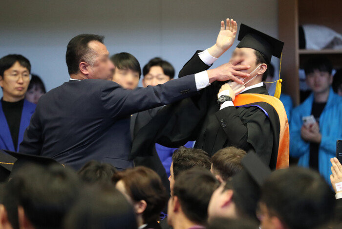 16일 대전 유성구 한국과학기술원(KAIST)에서 열린 ‘2024년 학위수여식’에서 졸업생 신분으로 참석한 신민기 녹색정의당 대전시당 대변인이 윤석열 대통령에게 항의하자 경호원들로부터 제지를 당하고 있다. [뉴스1]