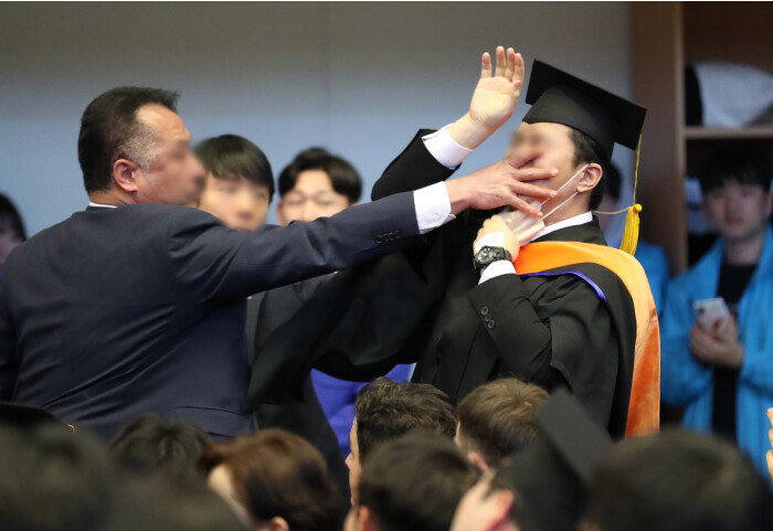 2월 16일 대전 유성구 한국과학기술원(KAIST)에서 열린 학위수여식에서 졸업생 자격으로 참석한 신민기 녹색정의당 대전시당 대변인이 학교를 방문한 윤석열 대통령에게 항의하다 경호원들로부터 제지를 당하고 있다. [뉴스1]