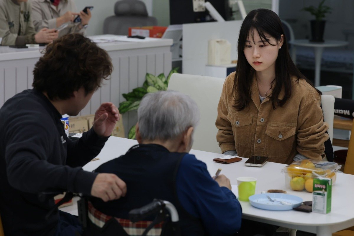 10월 26일 경기 화성의 한 요양원에서 ‘헌트: 치매 머니 사냥’의 주인공 강대용 씨(가운데)를 처음 만났다. 면회실에서 아들(왼쪽)과 필담을 나누는 모습을 필자가 바라보고 있다. 이틀 뒤 아버지 대용 씨는 갑작스레 세상을 떠났다.