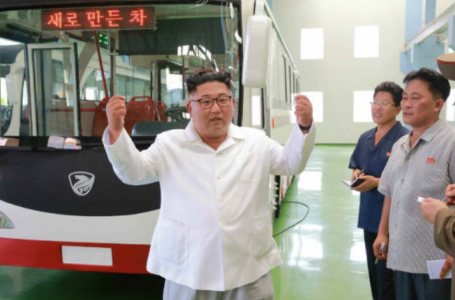 김정은 북한 국무위원장이 8월 4일 북한 기술로 만들었다는 새 버스 앞에 서서 두 손을 들고 있다.[조선중앙통신]