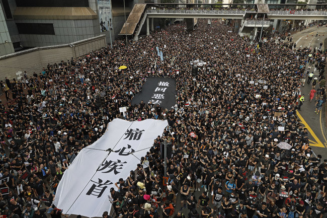 6월 16일 홍콩 시내에서 '범죄인 인도 법안' 철회를 주장하는 시위가 열리고 있다. 시위대가 든 흰색과 검은색 걸개에는 각각 ‘철회악법’(撤回惡法, 악법을 철회하라), ‘통심질수’(痛心疾首, 매우 증오하고 미워한다)라는 글이 써있다.
[AP/뉴시스]