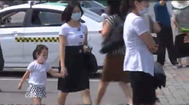 어린이가 마스크를 쓴 채 어머니 손을 잡고 평양 거리를 걷고 있다.
