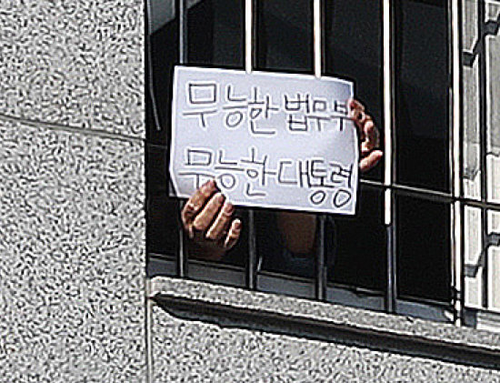1월 6일 서울 송파구 동부구치소에서 한 재소자가 ‘무능한 법무부, 무능한 대통령’이라는 문구가 적힌 종이를 창살 너머로 꺼내 보이고 있다. [뉴스1]