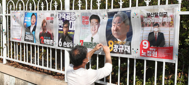 4·7 부산시장 보궐선거 공식 선거운동이 시작된 3월 25일 부산 해운대구 한 아파트 정문에서 인근 주민센터 관계자들이 부산시장 보궐선거 선거벽보를 부착하고 있다. [뉴스1]