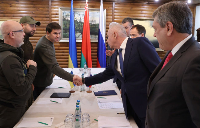 러시아 대표단(오른쪽)과 우크라이나 대표단(왼쪽)이 3월 3일 벨라루스 브레스트의 회담장에서 2차 정전 회담을 시작하기에 앞서 서로 악수하고 있다. [뉴시스]