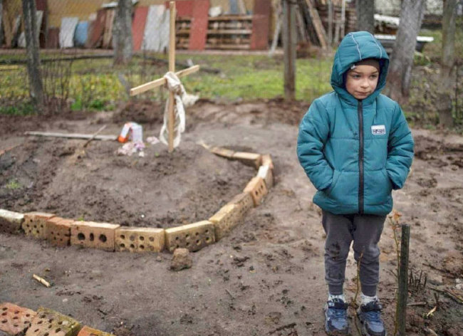 4월 6일 우크라이나 수도 키이우의 한 가정집 마당에 전쟁으로 인한 굶주림으로 숨진 여성의 무덤이 마련됐다. 엄마의 무덤 옆에 남자 아이가 침울한 표정으로 서 있다. [우크라이나 국방부 트위터]
