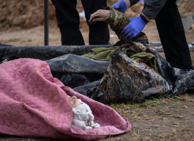 4월 6일 우크라이나 부차의 공동묘지에서 경찰이 러시아군 점령 당시 숨진 민간인들의 시신을 안치소로 보내기에 앞서 신원 확인 작업을 하고 있다. [AP/뉴시스]