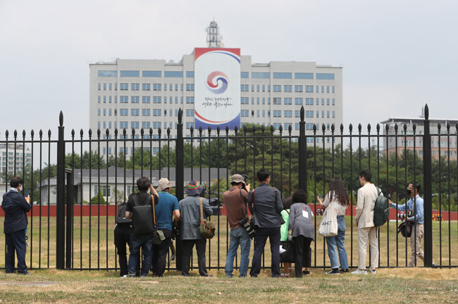 시범 개방 첫날인 6월 10일 서울 용산구 용산공원을 찾은 시민들과 취재진이 대통령실 청사 앞 공원을 둘러보고 있다. [뉴스1]