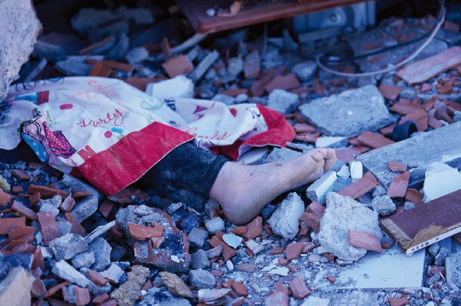 강진으로 파괴된 건물 아래 죽은 아이의 발이 보인다. [뉴시스]