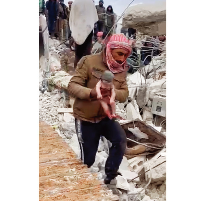 2월 7일 시리아 진데리스 마을에서 구조대원이 파괴된 구조물의 잔해에서 여자 아기를 구조해 안전한 곳으로 옮기고 있다. [뉴시스]