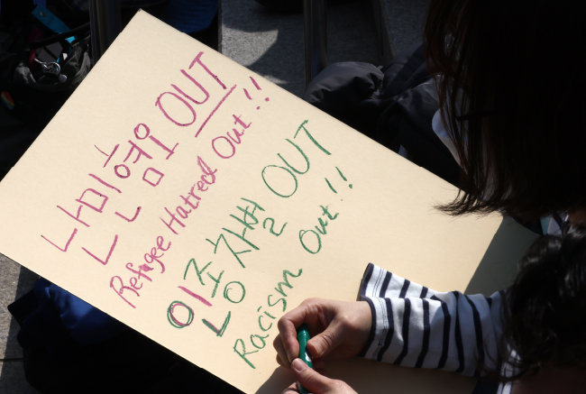 3월 19일 서울 중구 서울역 광장에서 열린 ‘2023 세계 인종차별 철폐의 날 기념대회’에서 한 참여자가 난민 혐오 근절을 촉구하는 문구를 적고 있다. [뉴스1]