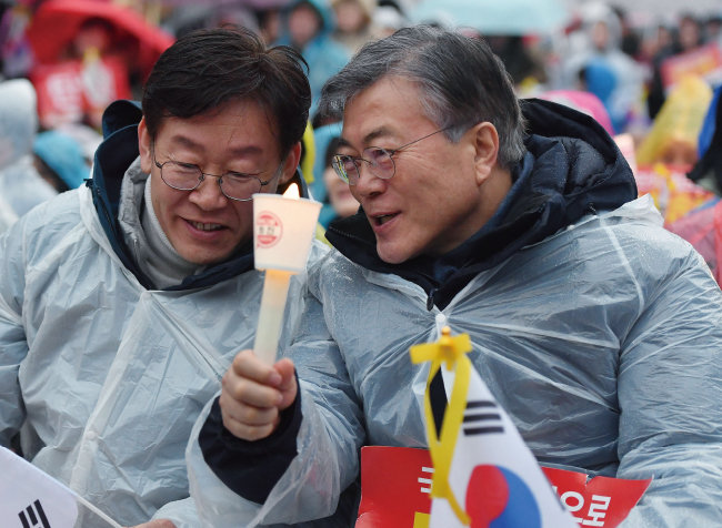 2017년 3월 1일 문재인 당시 더불어민주당 전 대표(오른쪽), 이재명 당시 성남시장이 서울 광화문광장에서 열린 ‘박근혜 대통령 탄핵 촉구 촛불집회’에 참석해 대화하고 있다. [뉴시스]