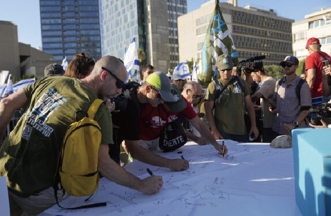  6월 19일 이스라엘 예루살렘에서 열린 사법 조정안 반대 시위에서 이스라엘 예비군들이 복무 거부 선언에 동참하는 서명을 하고 있다. [AP뉴시스]