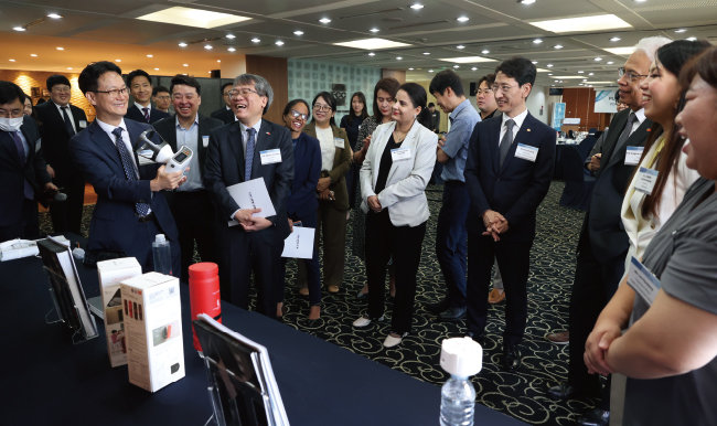 김윤상 조달청장(오른쪽에서 네 번째)이 주한 외교사절단을 초청한 조달 설명회에서 국산 혁신 제품 소개를 들으며 웃고 있다. [조달청]
