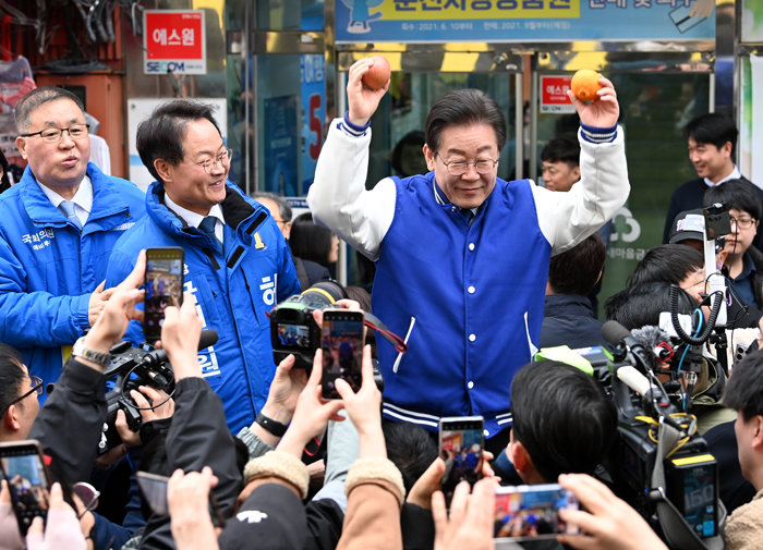 19일 이재명 더불어민주당 대표가 강원 춘천시 명동거리를 방문해 한라봉과 사과를 들고 인사를 나누고 있다. [뉴스1]