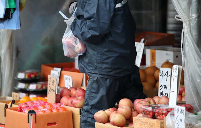 5일 서울 송파구 가락시장에서 한 시민이 사과를 사서 발걸음을 옮기고 있다. [뉴스1]