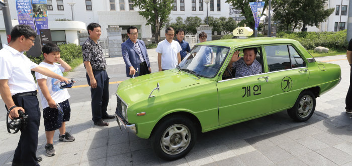 영화 ‘택시운전사’에 등장한 포니 택시가 2017년 8월 20일 광주 동구 옛 전남도청 앞 5·18민주광장에 전시돼 시민들이 기념 촬영을 하고 있다. [동아DB]