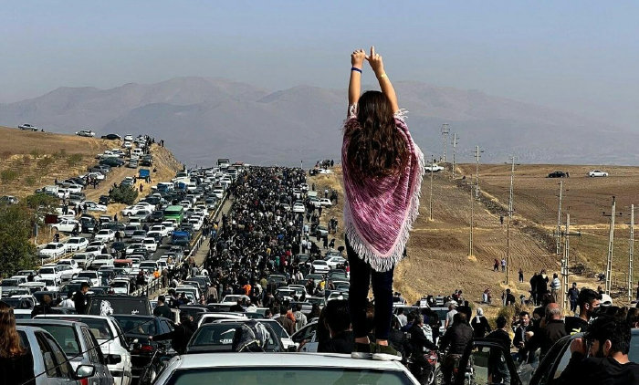 히잡을 쓰지 않은 한 이란 여성이 2022년 10월 26일 서부 쿠르디스탄주 사케즈로 향하는 도로에서 차량 위에 올라 당국의 탄압에 항거한다는 의미로 두 손을 치켜들었다. 히잡을 제대로 쓰지 않았다는 이유로 경찰에 끌려간 후 의문사한 22세 쿠르드족 여성 마사 아미니의 묘지가 있는 사케즈로 향하는 도로는 추모 인파와 차량 행렬로 가득 찼다. [X 캡처]