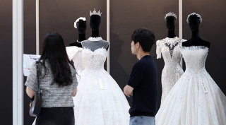 7월 6일 서울 강남구 삼성동 코엑스에서 열린 ‘2025 추계 웨덱스 웨딩 박람회’에서 예비 부부들이 전시된 드레스를 살펴보고 있다. 뉴스1