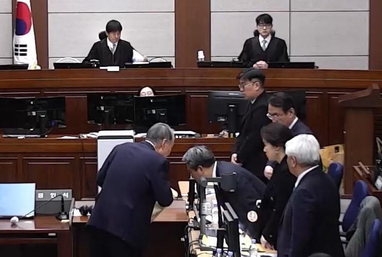 윤석열 전 대통령이 1월 13일 오후 서울 서초구 서울중앙지방법원에서 진행된 내란 우두머리 혐의 2차 결심공판에 출석해 배보윤 변호사와 대화를 나누고 있다. 서울중앙지방법원 제공 영상 캡처