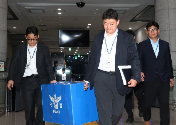 투표용지 부족 사태를 수사하는 검경 합동수사본부 수사관들이 6월 11일 경기 과천 중앙선거관리위원회 압수수색을 마친 뒤 압수품을 들고 건물을 나오고 있다. 뉴스1