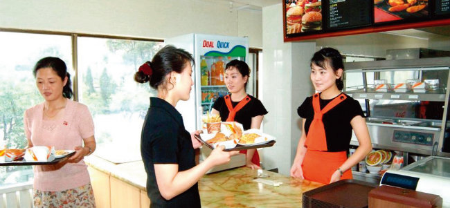 평양 시민들이 싱가포르 패스트푸드 체인점 ‘삼태성’에서 햄버거를 사고 있다. [북한 조선중앙통신]