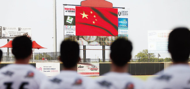 중국 야구 국가대표 선수들이 전체의 73%를 차지하는 텍사스 에어호그스 팀이 7월 18일 경기 시작 전 전광판에 뜬 중국 국기에 경례를 하고 있다. [뉴시스=AP]