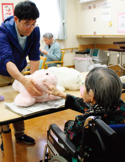 2017년 일본 한 요양시설에서 복지사가 로봇 인형을 이용해 노인을 치료하고 있다. [동아DB]