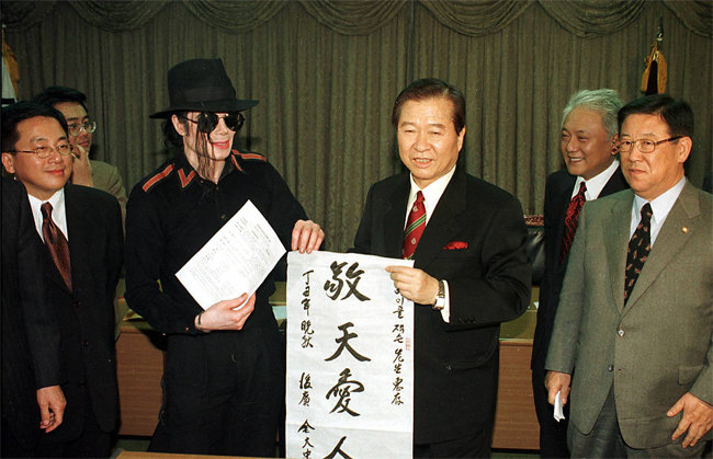 1997년 11월 마이클 잭슨(왼쪽 두 번째)이 방한했을 당시 김대중 전 대통령이 ‘경천애인’이란 글을 써 보여주고 있다. [동아DB]