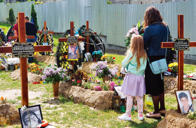 5월 17일(이하 현지 시간) 우크라이나 서부 르비우의 이반 프란코 공원에 조성된 임시 묘소에서 가장을 잃은 가족이 기도하고 있다.