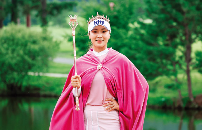 윤이나가 한국여자프로골프협회(KLPGA) 투어 에버콜라겐 퀸즈크라운 2022에서 우승한 후 시상식에서 왕관에 망토를 두르고 왕권을 상징하는 셉터(scepter)를 들고 있다. [사진 제공 · KLPGA]