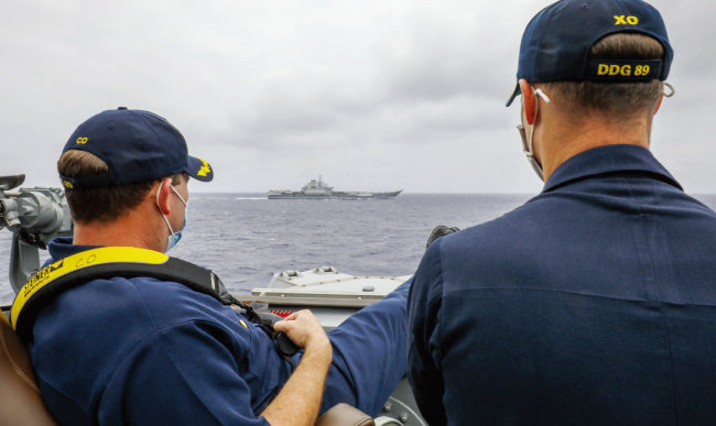 지난해 4월 필리핀해에서 미 해군 이지스 구축함 ‘머스틴’의 함장(왼쪽)이 함교 난간에 다리를 올린 채 중국 해군 항공모함 랴오닝함을 바라보고 있다. 남중국해에서 양국 해군이 벌이는 신경전을 상징적으로 보여준다. [사진 제공 · 미 해군]