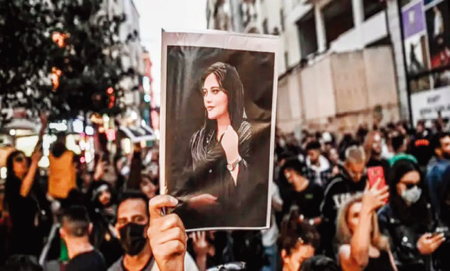 이란 여성들이 의문사한 마흐사 아미니의 사진을 들고 히잡 반대 시위를 하고 있다. [트위터]