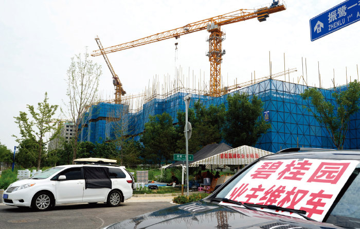 지난해 8월 17일 디폴트 위기에 빠진 중국 1위 건설사 비구이위안 (碧桂園·컨트리가든)이 베이징 외곽에 건설 중인 아파트 앞 차량 유리에 “주택 소유자의 권리를 보호하라”고 쓴 팻말이 올려 있다. [뉴시스]