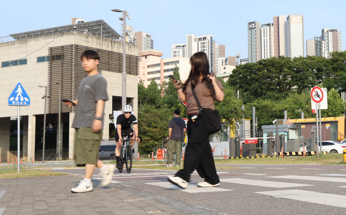 휴대폰을 보면서 한강 시민공원 자전거 도로 횡단중인 시민. 신호가 없는 자전거 도로의 횡단은 좌우측 자전거 운행에 더욱 주의를 기울여야 한다.  사진=박해윤 기자