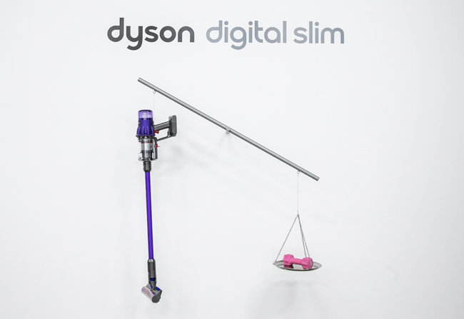 2kg 아령과 다이슨 디지털 슬림™을 저울에 올려 무게를 비교하고 있다.