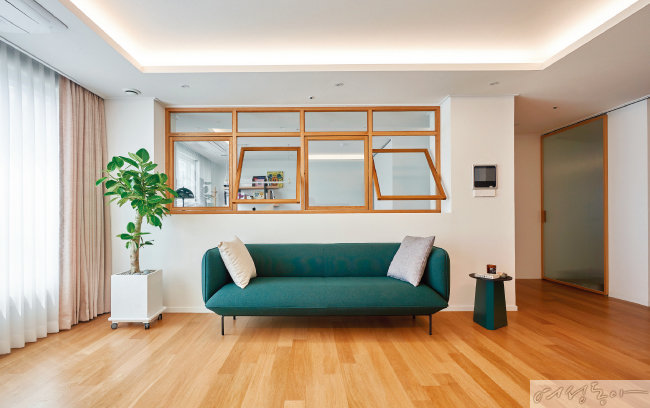 블루그린 컬러 소파와 360도 회전 가능한 원목 창, 우드 소재 바닥재를 사용해 자연스럽고 편안한 공간 연출이 완성됐다.