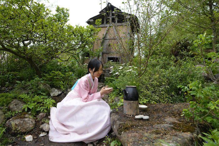 황지해 작가가 만든 정원에서 한국의 차를 마시는 포즈를 취하고 있는 전시팀 관계자.