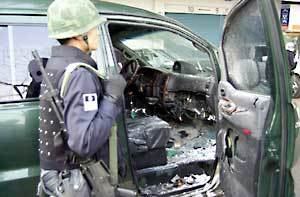 폭발물이 터진 차량에서 무장한 군 폭발물 조사반이 현장조사를 실시하고 있다.