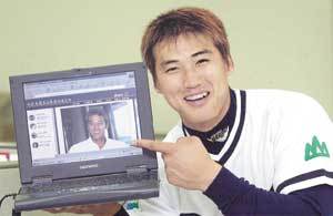 두산 홍성흔이 자신의 인터넷 홈페이지에 뜬 사진을 가리키며 환하게 웃고 있다.