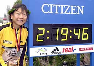 다카하시 나오코가 세계 최고기록을 세운 뒤 타임보드 옆에서 활짝 웃고 있다.