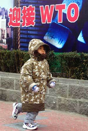 한 어린아이가 'WTO를 맞이하다' 라는 글귀가 적혀있는 베이징 시내를 지나고 있다